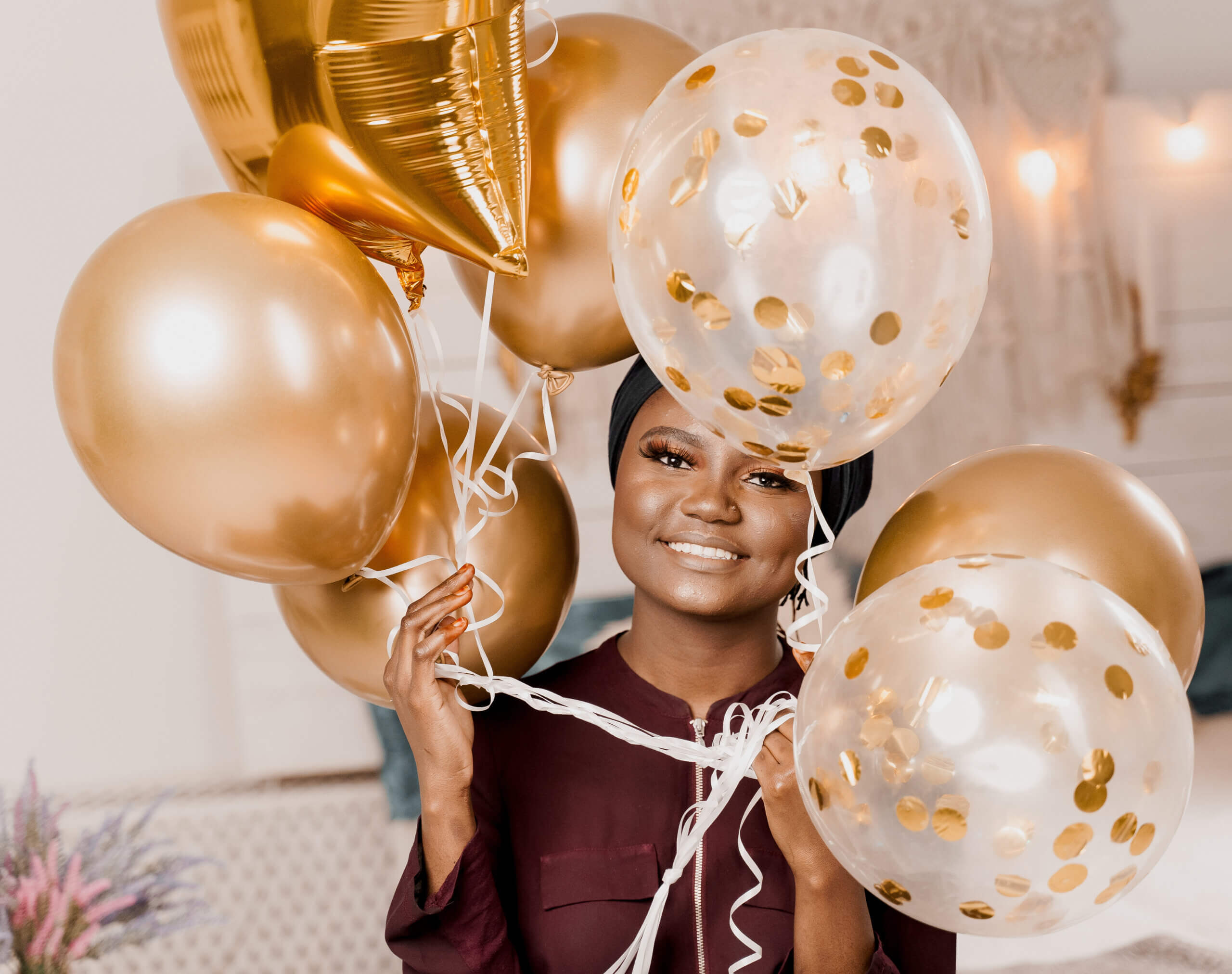 Frau die mehrere goldenen und weiß gepunkete Luftballons hält.