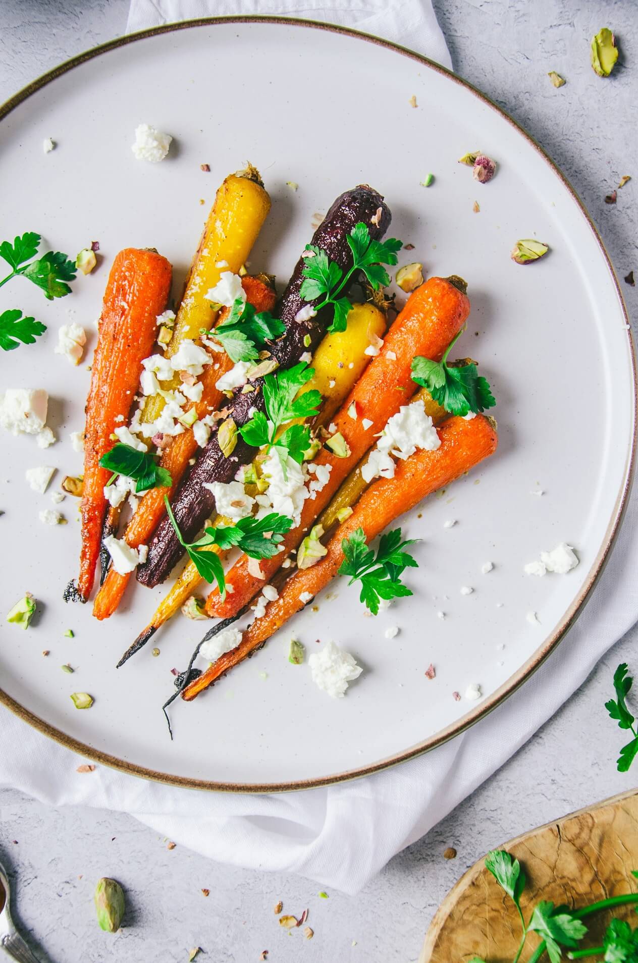 Ein Teller mit geschmorten bunten Karotten und einem veganen Feta Topping.